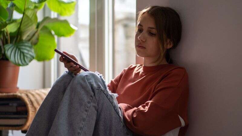 Sad teenager looking down on mobile phone